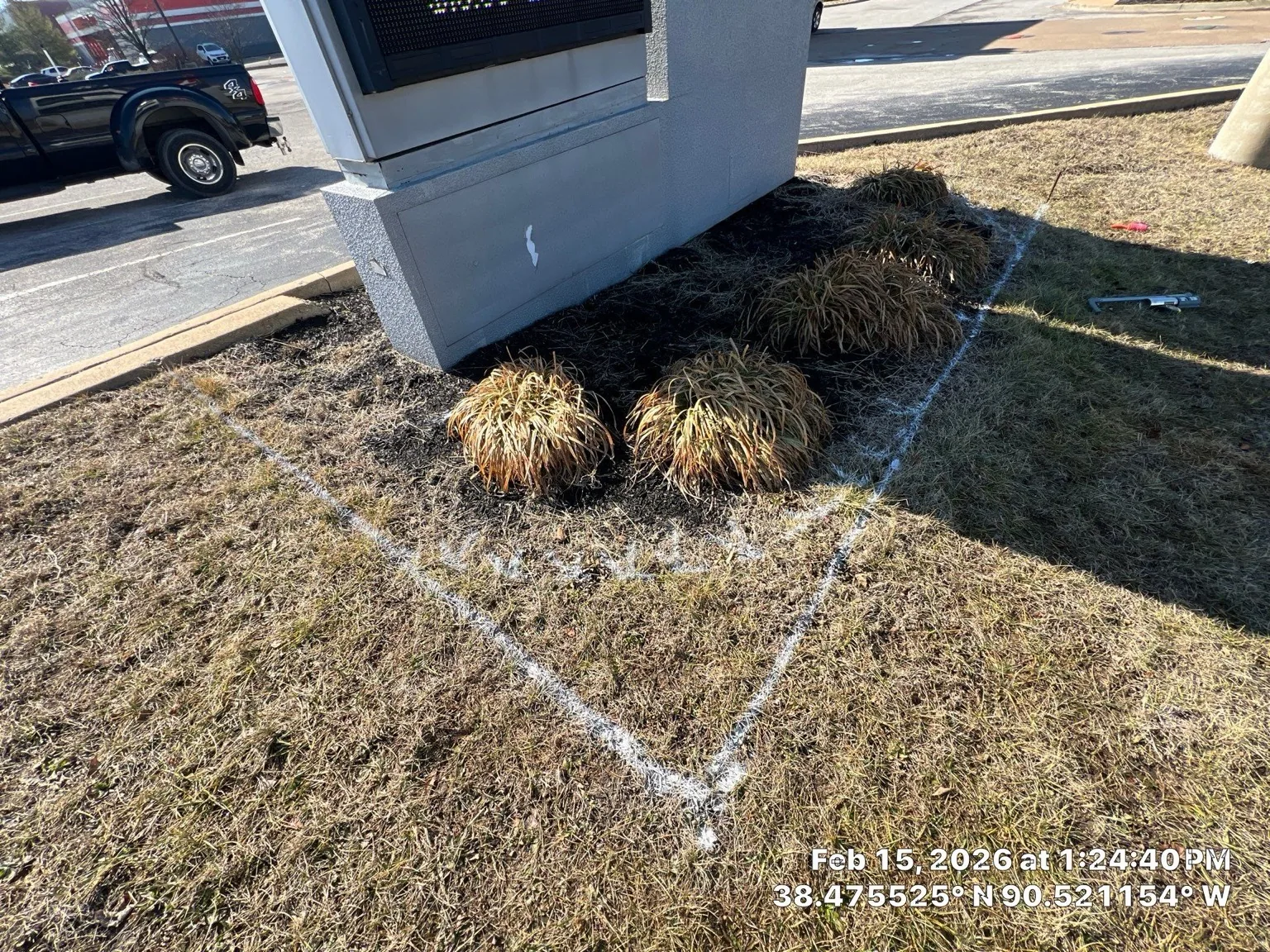 Worn planting bed around a commercial sign before renovation