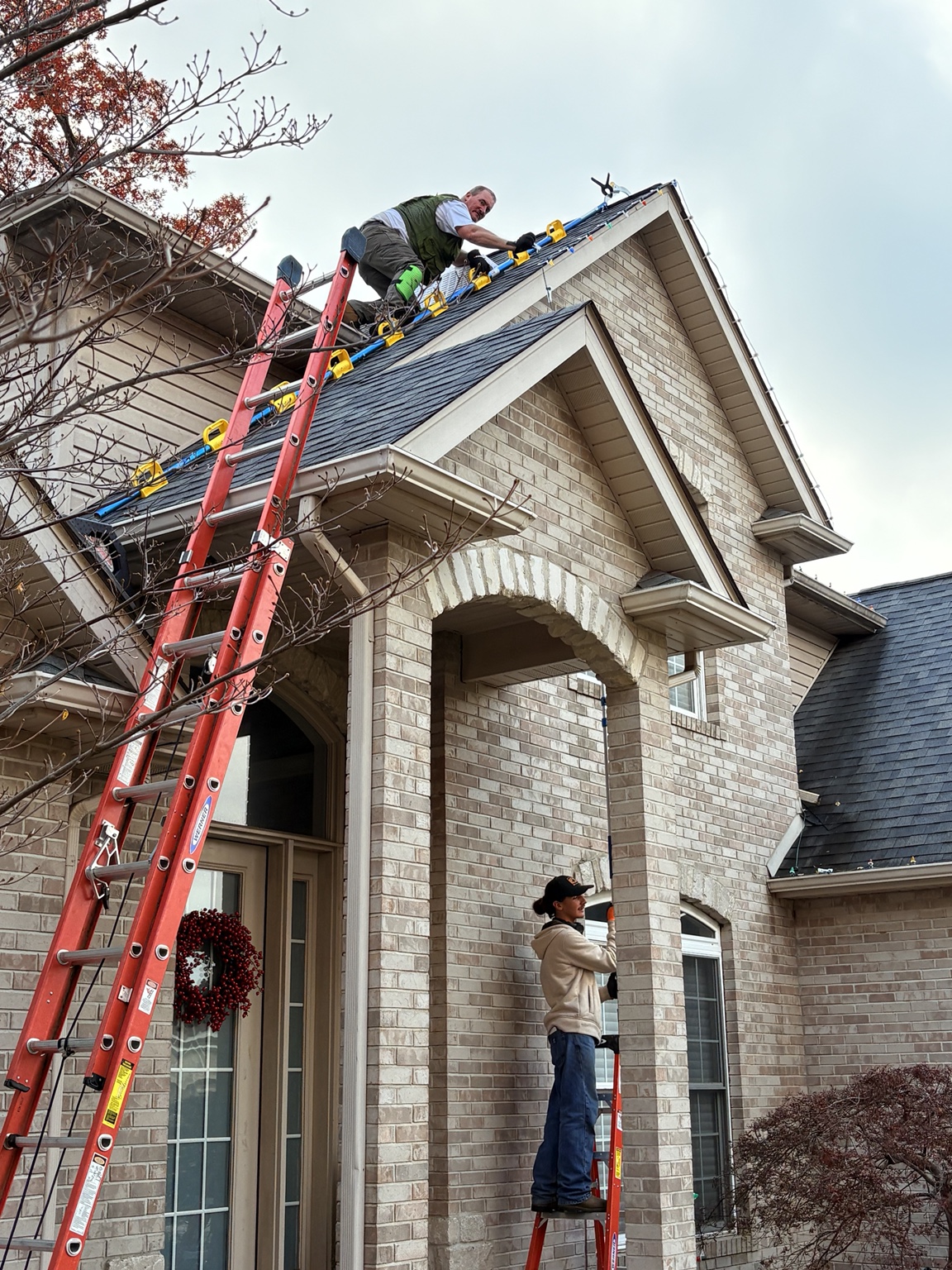 Professional Christmas-light installation crew working on a roofline