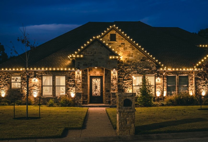 Warm-white roofline lighting on a stone home