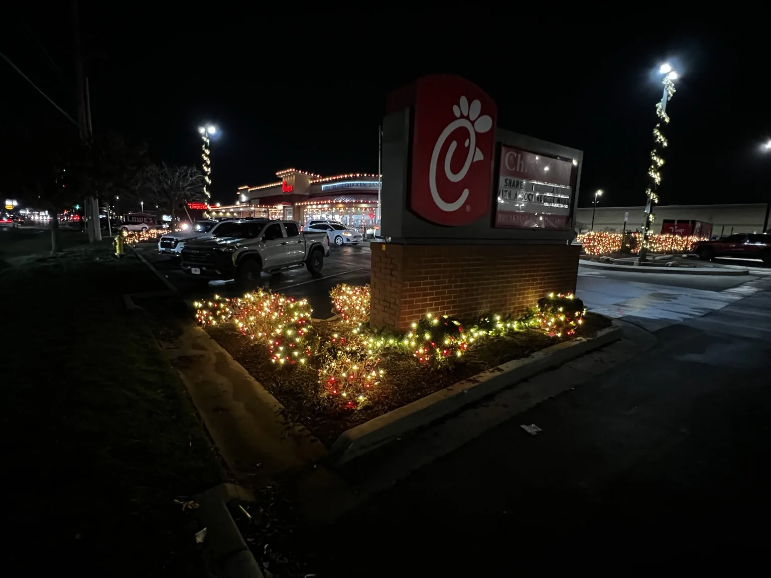 Christmas lights around a commercial property sign and landscaping