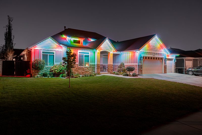 Multicolor lighting along the front roofline and garage of a single-story home