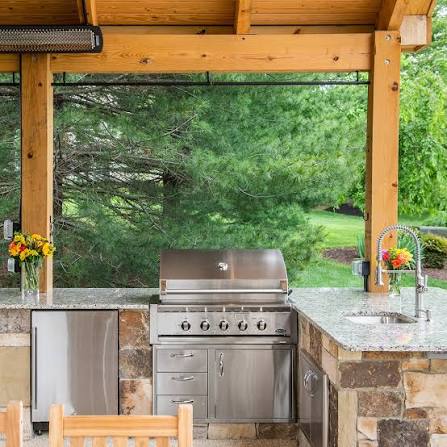 Covered outdoor kitchen with stainless grill and stone counters