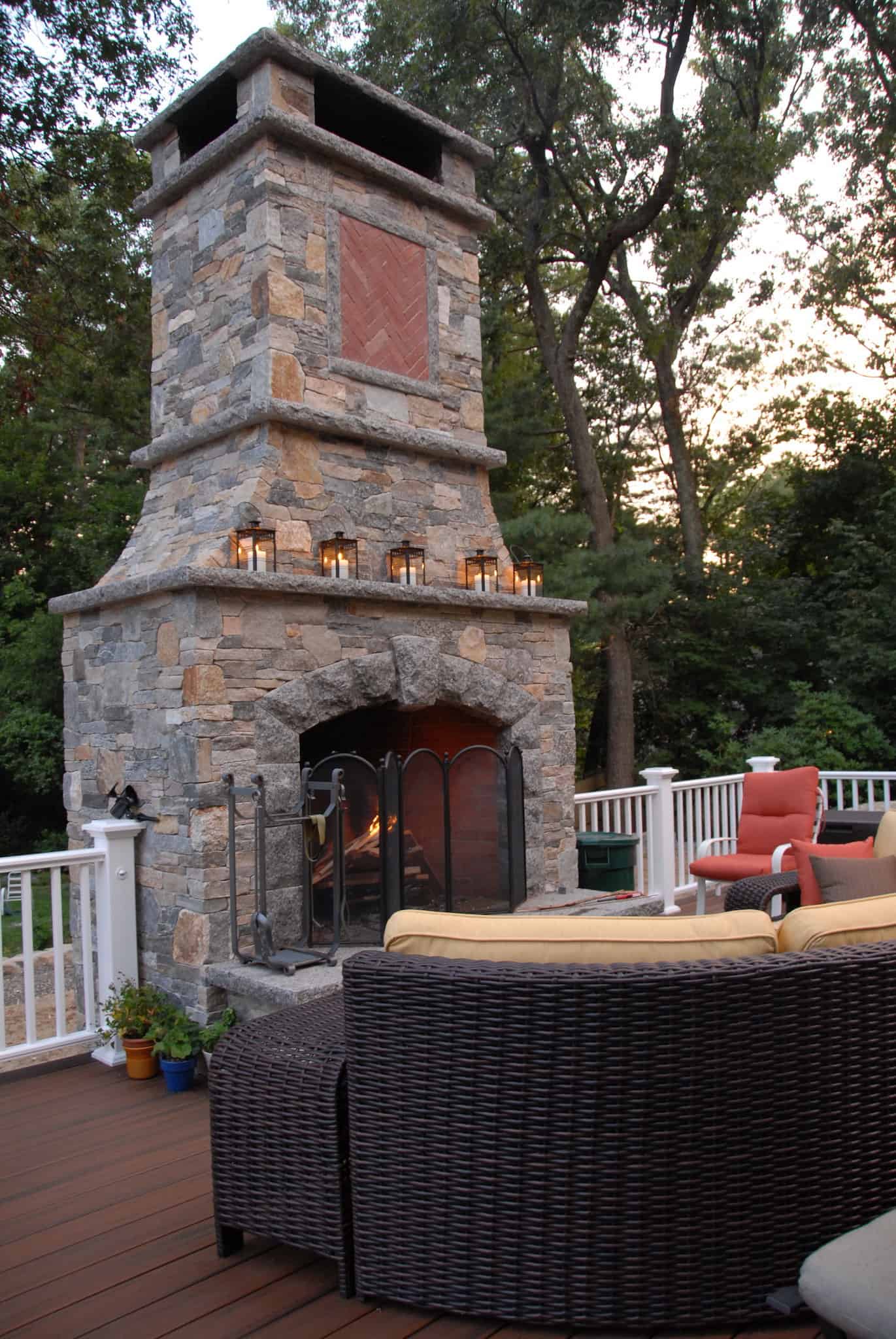 Tall stone outdoor fireplace beside deck seating