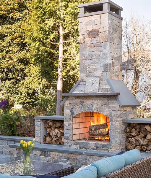 Freestanding stone fireplace with firewood storage