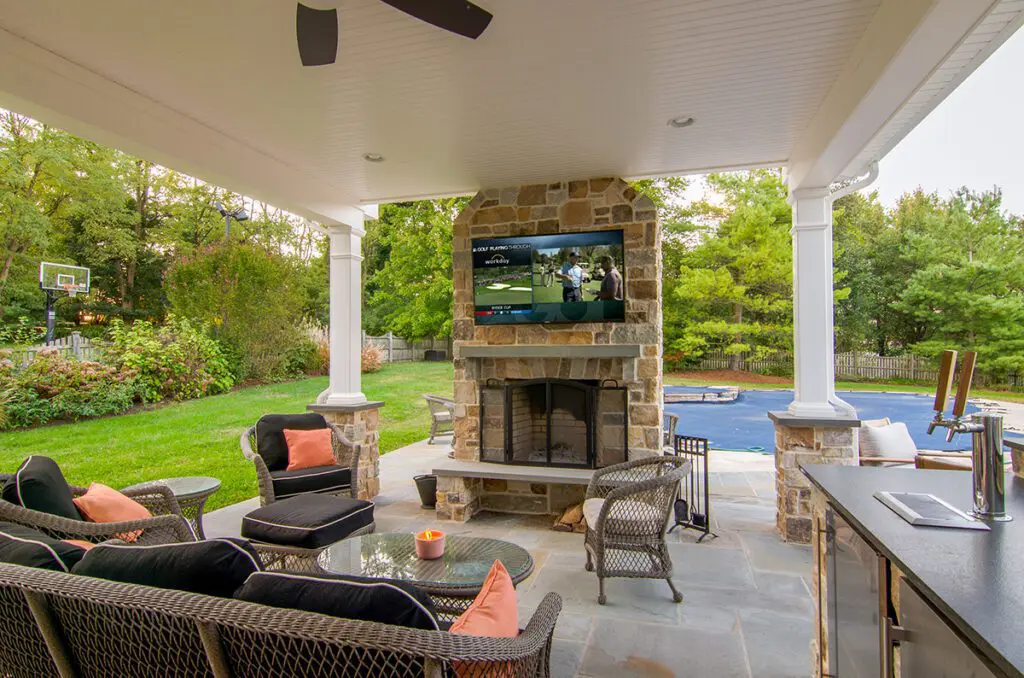 Covered patio with stone fireplace and pool view