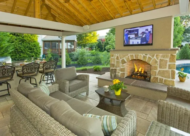 Covered outdoor lounge with a burning stone fireplace
