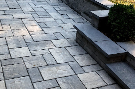 Gray paver patio with raised stone wall and steps