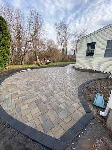 Curved backyard paver patio with contrasting dark border